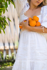 Woman in white dress collecting oranges from the garden