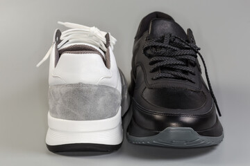 One black and one white sneaker, front and back view