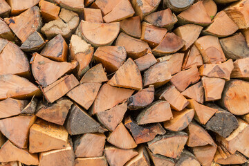 Woodpile of split firewood stacked in a row outdoors