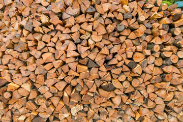 Woodpile of split firewood stacked in a row outdoors