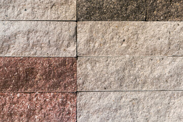 Wall faced with rough rectangular red and gray stone tiles