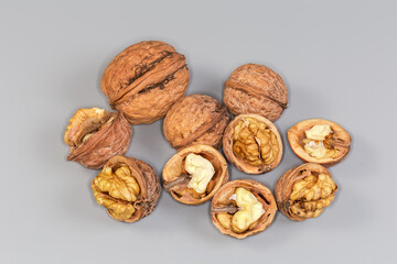 Dry whole and split walnuts on a gray background