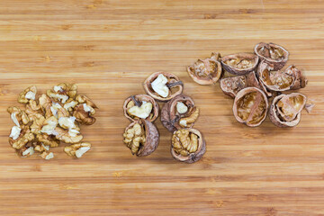 Peeled and split walnuts, their empty shells on wooden surface