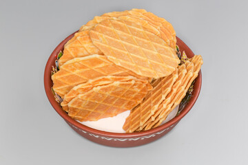 Sweet round wafers in clay bowl on a gray background