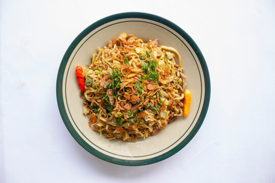 "Mie Goreng Jawa or bakmi jawa or java noodle with spoon and fork. Indonesian traditional street food noodles from central java or Yogyakarta, indonesia on white background."