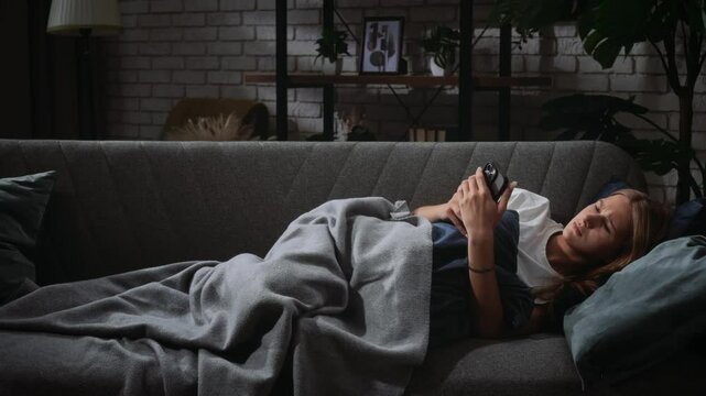 Woman Relaxing and Browsing on Smartphone While Lying on Sofa