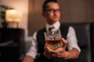 Businessman holding a glass of whiskey and drinking on a sofa.