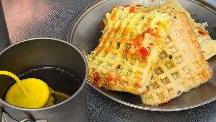 Crispy, golden-brown vegetable waffles with visible ingredients like kimchi and scallions, served hot with dipping oil.