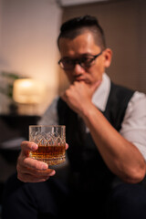 Businessman holding a glass of whiskey and drinking on a sofa.