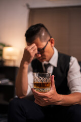 Businessman holding a glass of whiskey, sitting and drinking	