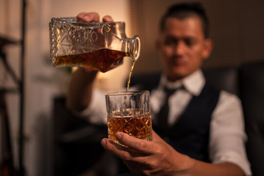 Businessman holding a glass of whiskey and drinking on a sofa.