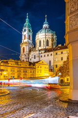 A blurred tram moves through Lesser Town Square in Prague at night, with the stunning architecture...