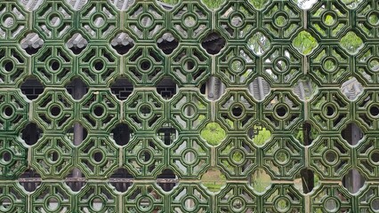 Close-up of intricate green lattice tiles in traditional Chinese architecture, showing symmetry and...