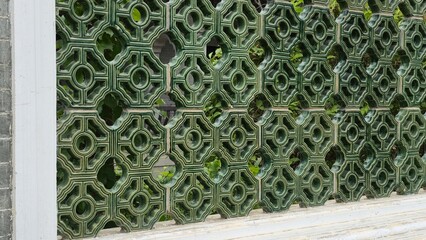 Detailed view of a traditional Chinese lattice screen with intricate green ceramic patterns.