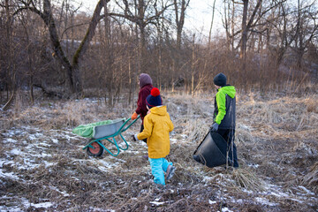 In a serene winter landscape, children engage in a delightful exploration of nature as they gather various leaves and sturdy branches. Their teamwork shines through as they work together.