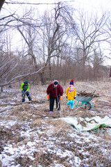 Helping hands gather wood for warmth during a chilly winter day in the woods, showcasing community spirit and teamwork among families and friends