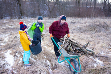 Family gathering sticks for firewood in a winter field while enjoying a chilly afternoon in the countryside, creating warmth together with teamwork and laughter