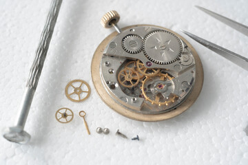 Close up of a professional watchmaker repairer working on an old vintage pocket watch in a workshop.