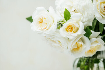 Closeup of white roses bouquet with green leaves in soft natural light