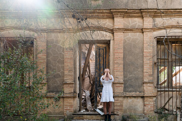 Woman standing with eyes closed next to the abandoned house