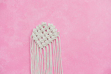 Macrame heart in progress on pink background