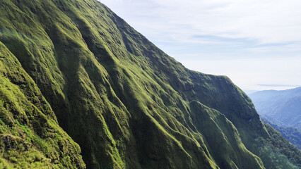 Summer mountain landscape with green grass and panoramic views of hills, trees, and sky