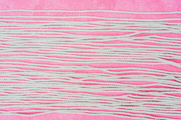 Rows of white macrame cords on pink background