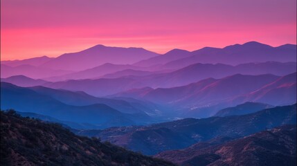 Fototapeta premium Dramatic twilight silhouette of a mountain range against a vibrant purple and pink sky
