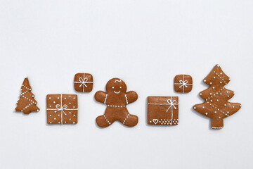 Fototapeta premium Decorated gingerbread cookies - trees, christmas presents and gingerbread man on a white background, copy space for text