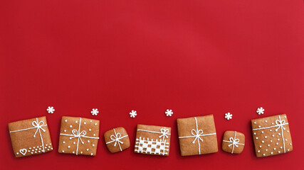 Decorated gingerbread cookies - christmas presents with small sugar snowflakes on a red background, copy space for text