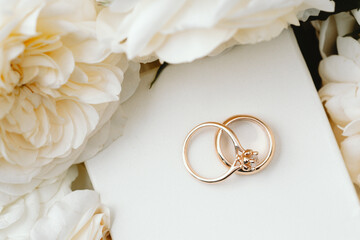 Gold rings on gift box with cream roses around