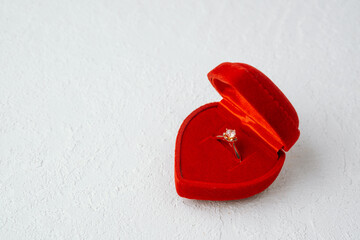 Solitaire engagement ring in red heart-shaped box on white background