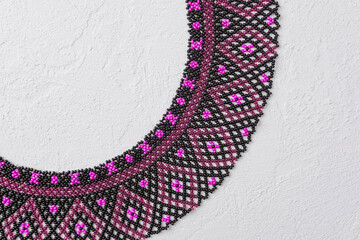 Black and pink beaded collar necklace with geometric pattern on white background