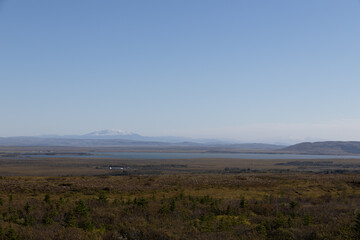 Vast landscape with distant snowcapped mountains under a clear blue sky and sprawling plains.