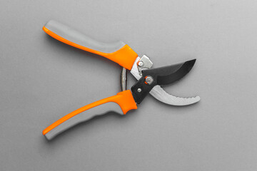Closed pruning shears with orange handles on gray background