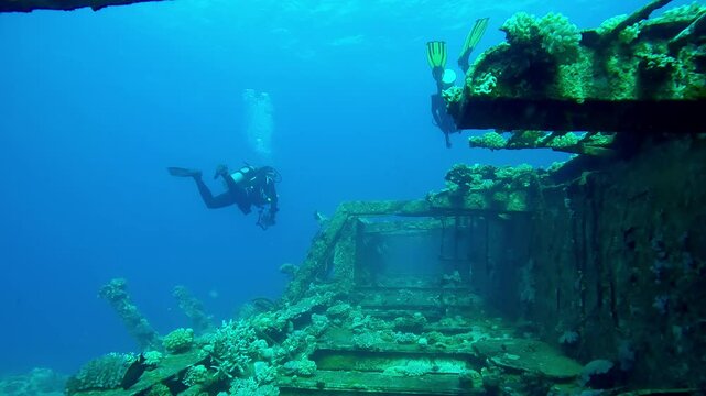 Scuba divers swim above corridor of upper deck in wreckship of Salem Express ferry, Slow motion of divers swims over hallway on deck of sunken ship