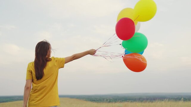 young girl with air beautiful balloons against blue sky. walk child nature. festive mood teenager. happy carefree. hold gel balls hand. blue green red orange yellow colors. fun one person journey