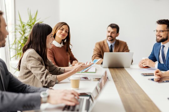 Businesswoman explaining charts and graphs on a meeting with coworkers in boardroom.