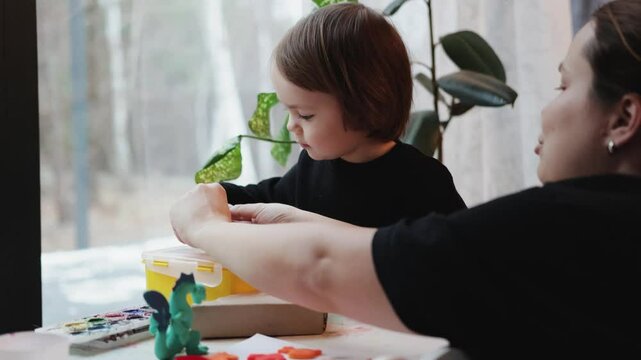 Child 3 years old and mother playing with toys at a children's table near the window in the house. Happy family, mother and daughter. Love and trust. Concept of a happy family.