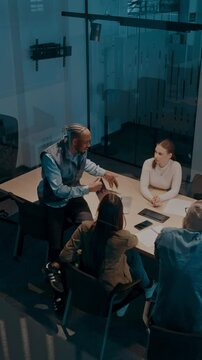 A diverse team of young professionals collaborates in a modern office conference room. Businesspeople discuss strategy, technology, and planning, using laptops to develop an innovative e-commerce
