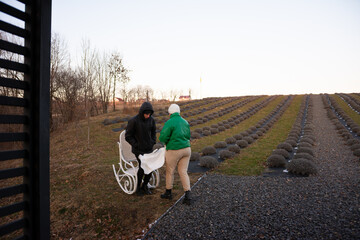 Two individuals engaging in conversation on a chilly evening at a lavender farm, surrounded by neatly arranged lavender plants and bare trees in the background