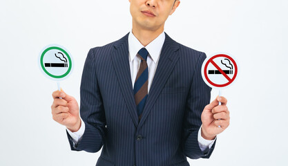 A middle-aged male business person holding a smoking sign and a no smoking sign