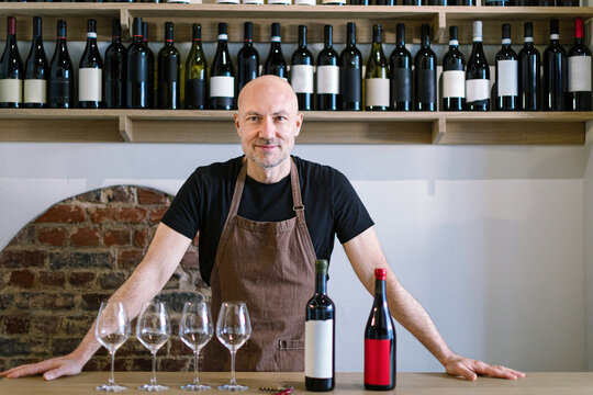 Wine shop owner presenting wine bottles and wine glasses