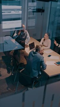 A diverse team of young professionals collaborates in a modern office conference room. Businesspeople discuss strategy, technology, and planning, using laptops to develop an innovative e-commerce