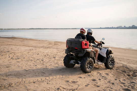 Exploring the sandy beach on an ATV during a calm afternoon with distant cityscape views