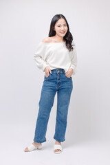 Full body portrait happy smile young asian beautiful woman curly hair wearing long sleeved shirt, blue jeans outfit, casual standing pose on white background joy positivity fashion lifestyle concept.