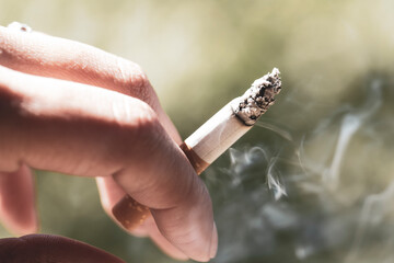 Woman smoking a cigarette. Smoke spreading. Blurred background, copy space.