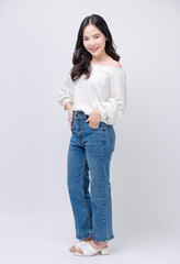 Full body portrait happy smile young asian beautiful woman curly hair wearing long sleeved shirt, blue jeans outfit, casual standing pose on white background joy positivity fashion lifestyle concept.