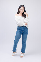 Full body portrait happy smile young asian beautiful woman curly hair wearing long sleeved shirt, blue jeans outfit, casual standing pose on white background joy positivity fashion lifestyle concept.