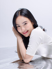 Portrait cheerful young asian beautiful woman curly hair wearing long sleeved shirt, black long pants outfit casual relax on floor in studio laydown on white background joy positivity fashion concept